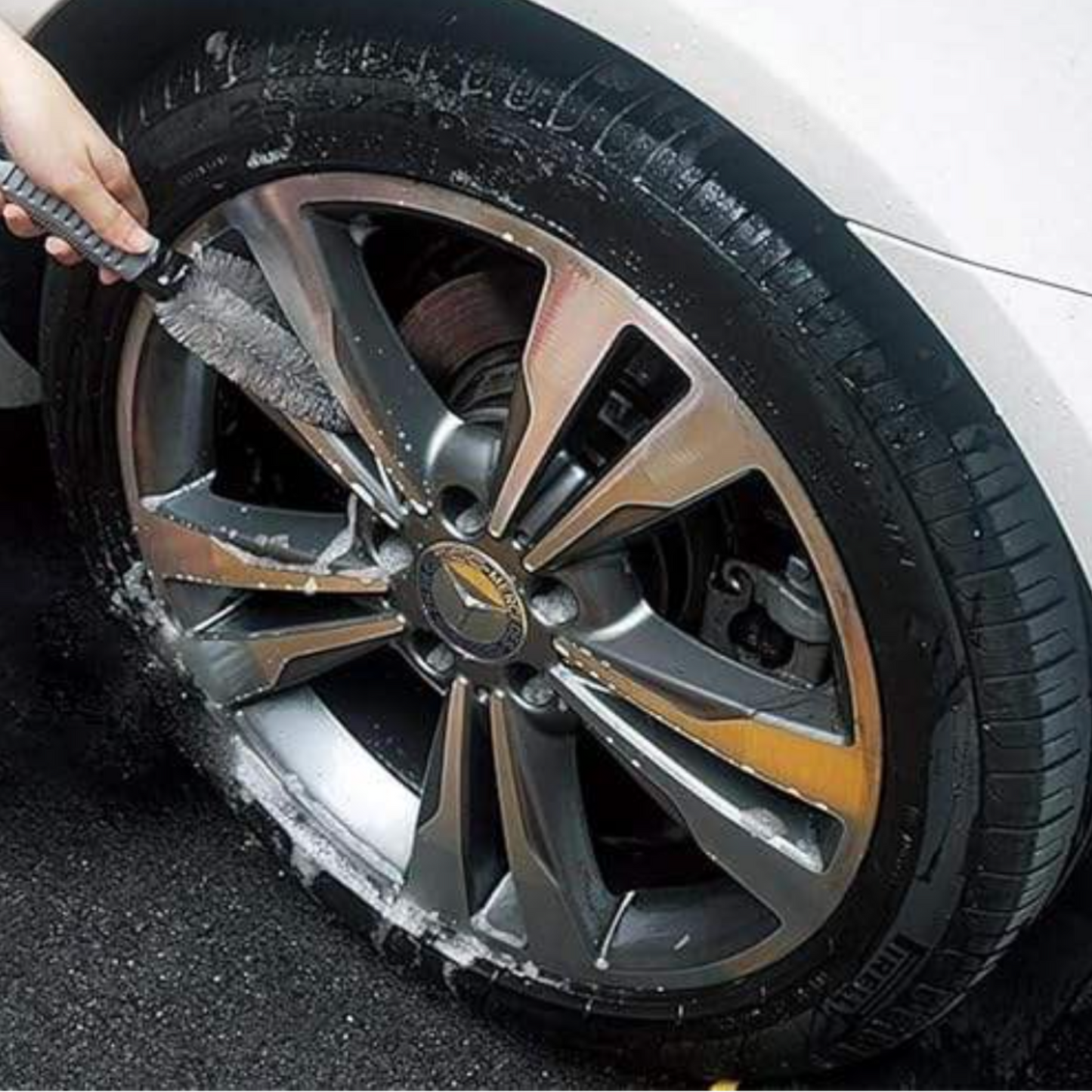 Person cleaning a car wheel with a brush